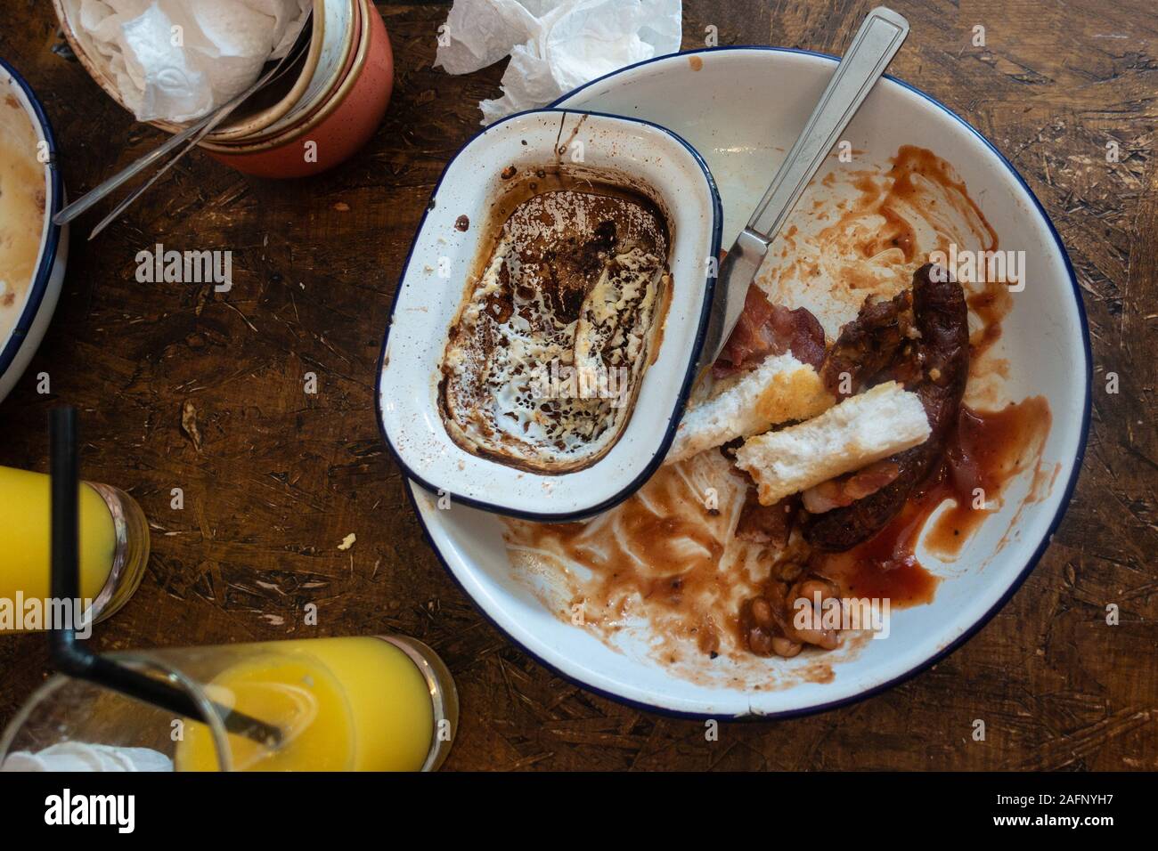 Un vuoto, sporco, rustico cercando piastra bianca su una tavola di legno alla fine di un pasto. Foto Stock