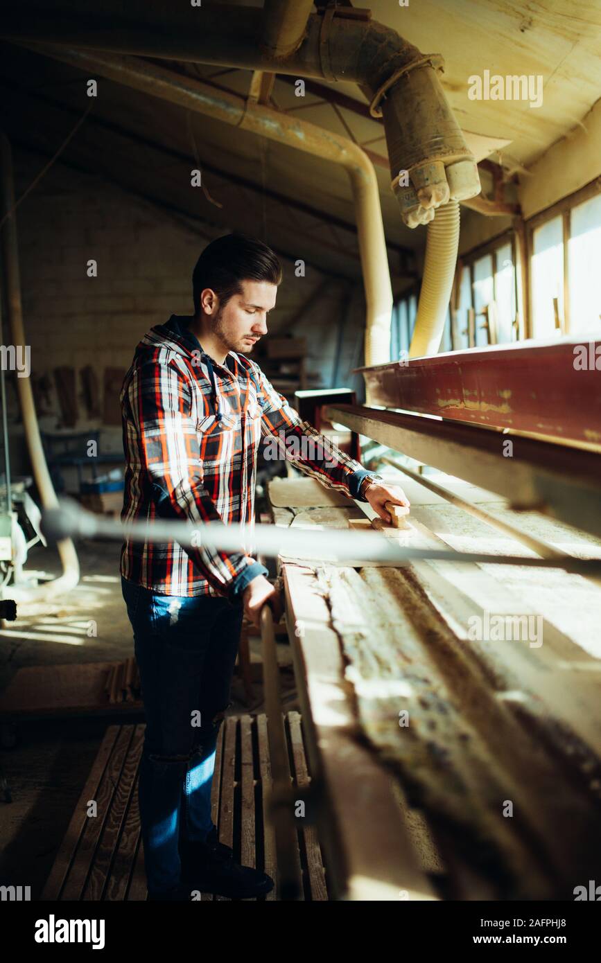 Uomo con tavola in legno con piano a mano nel laboratorio di falegnameria Foto Stock