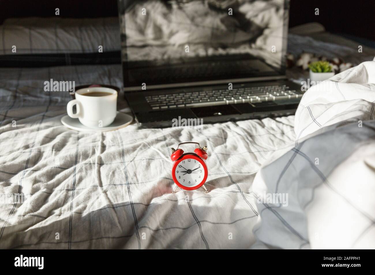 Close up sveglia rossa, il computer laptop e la tazza di caffè nel letto. Area di lavoro per freelance. Ora di scadenza del concetto. Lay piatto Foto Stock