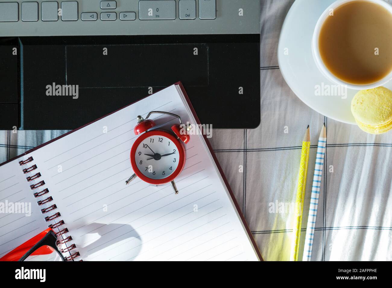 Close up sveglia rossa, il computer laptop e la tazza di caffè nel letto. Area di lavoro per freelance. Ora di scadenza del concetto. Lay piatto Foto Stock