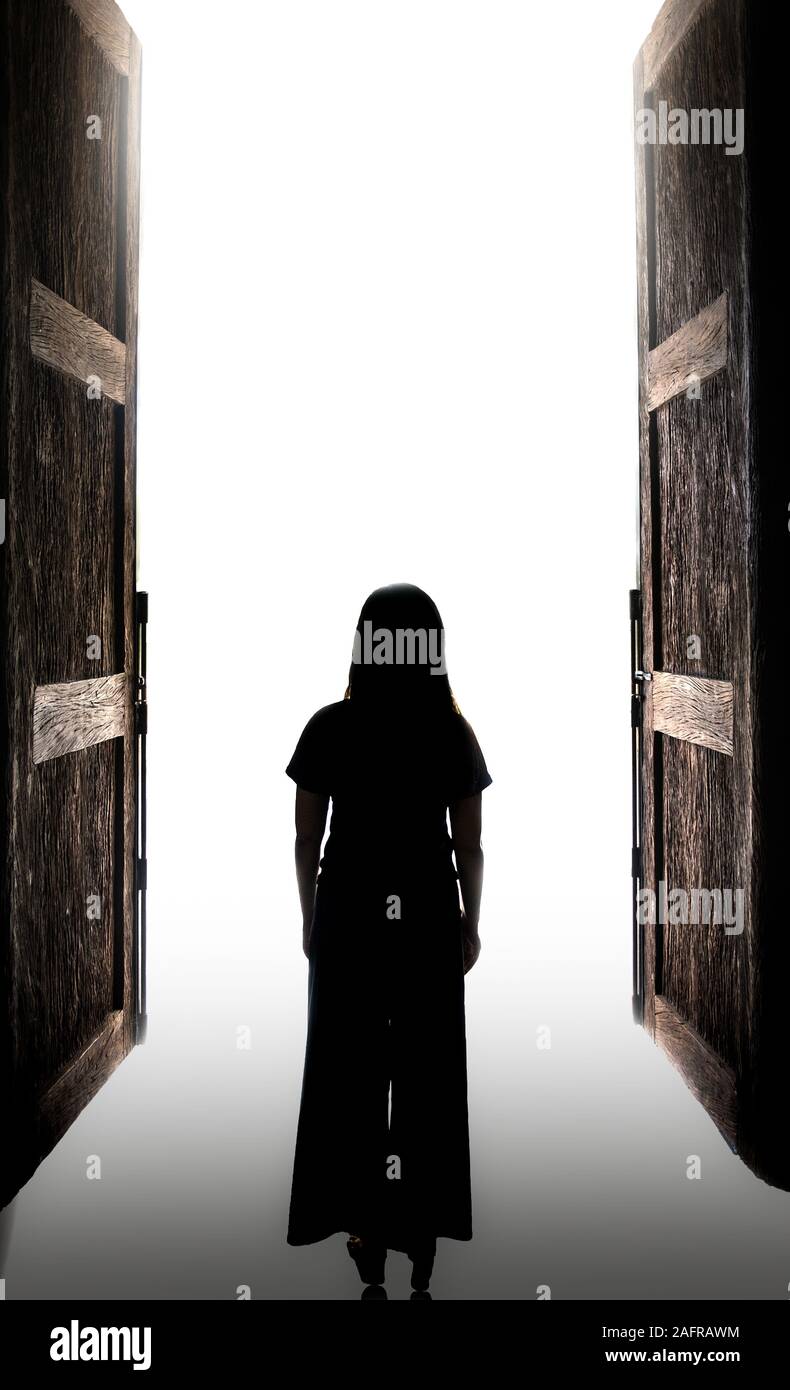 Donna in piedi nella luce aperta attraverso la grande porta, c'è una luce alla fine della destinazione Foto Stock