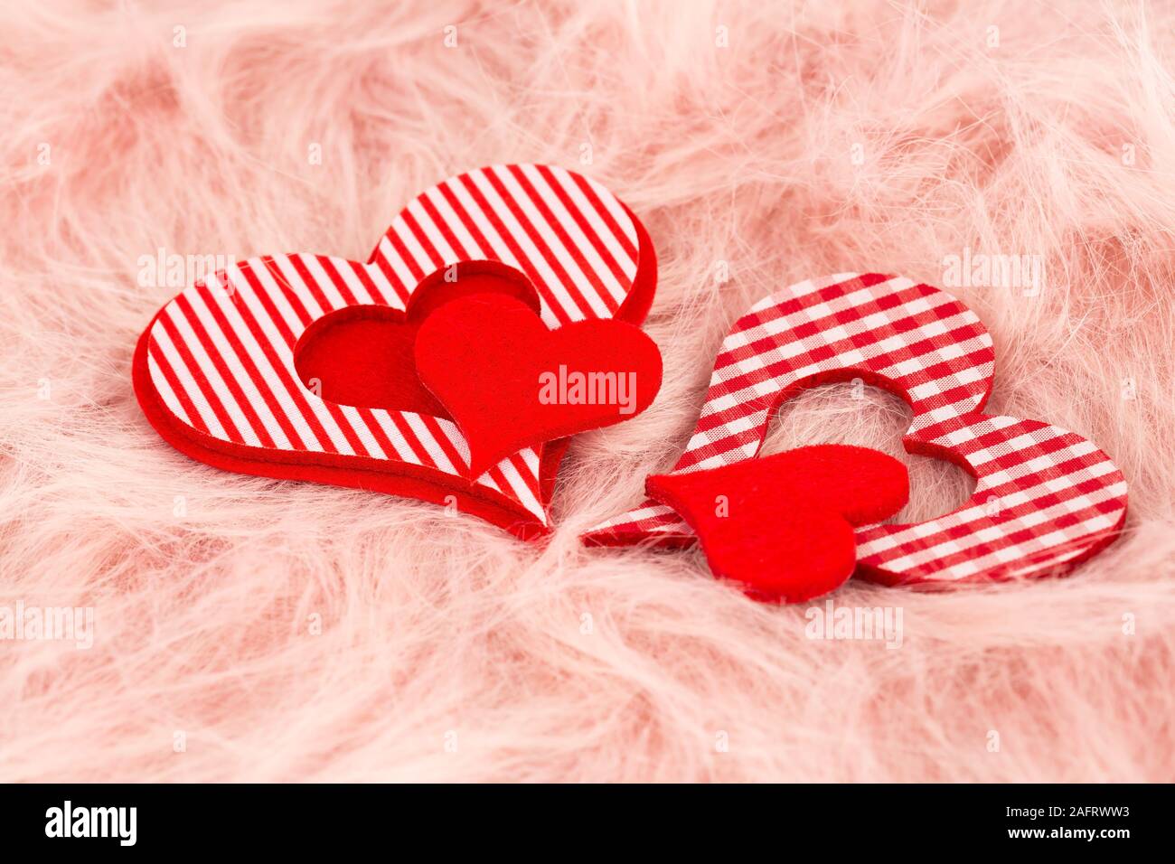 Due cuori rossi rosa su sfondo di pelliccia. Foto Stock