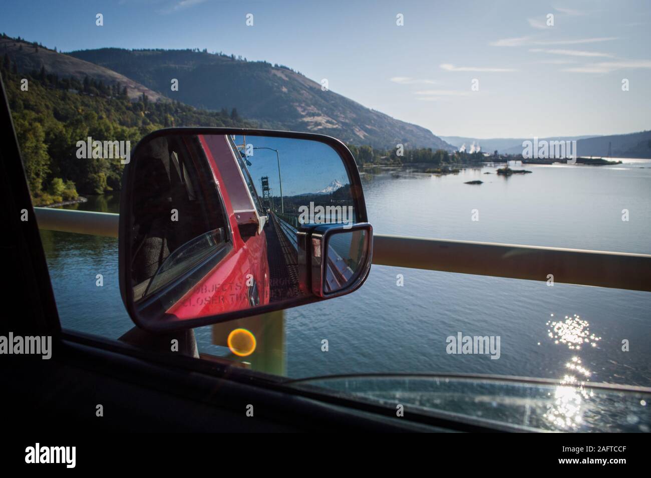 Guardando indietro la strada dietro in uno specchio a vista laterale, mentre si guarda fuori attraverso la gola Columbia viaggiando su un ponte su una strada viaggio. Foto Stock