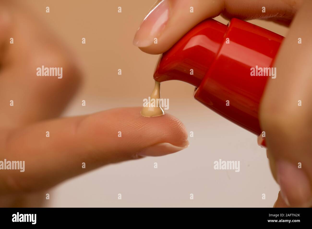 Donna sqeezing dalla pompa fondotinta liquido sul suo dito Foto Stock