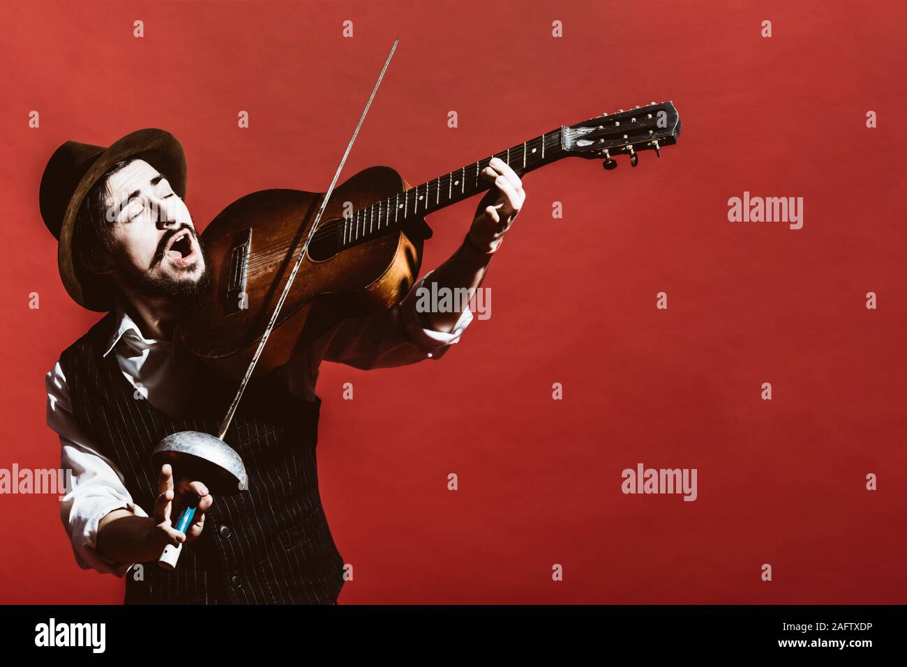 Guy positivo a suonare la chitarra e in posa Foto Stock