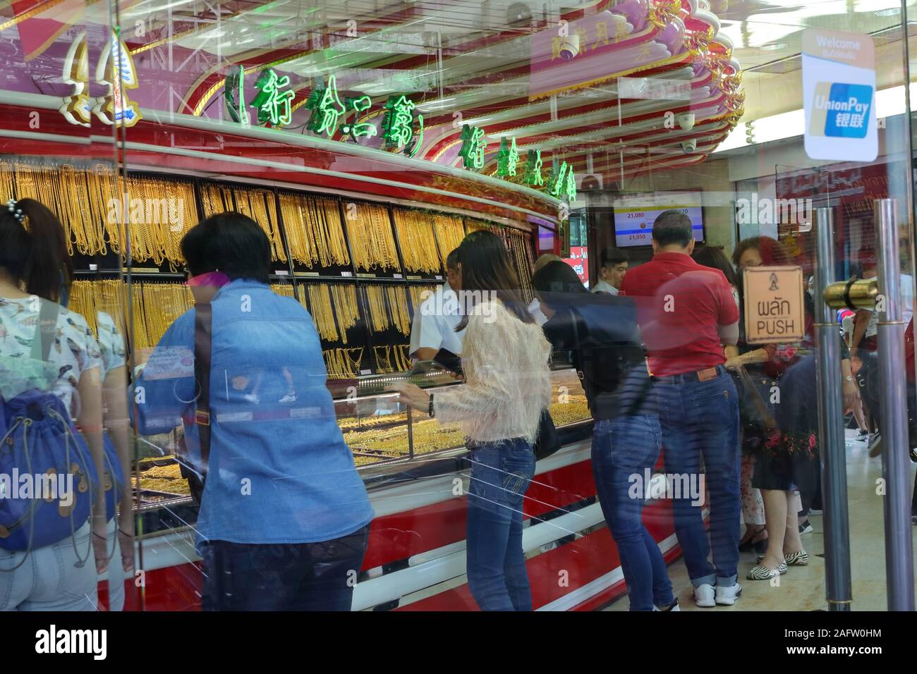 Bangkok, Tailandia - 16 Dicembre 2019 : messa a fuoco selettiva su oro collane appesi in vetrina nel negozio di oro a Chinatown, molti clienti nel negozio Foto Stock