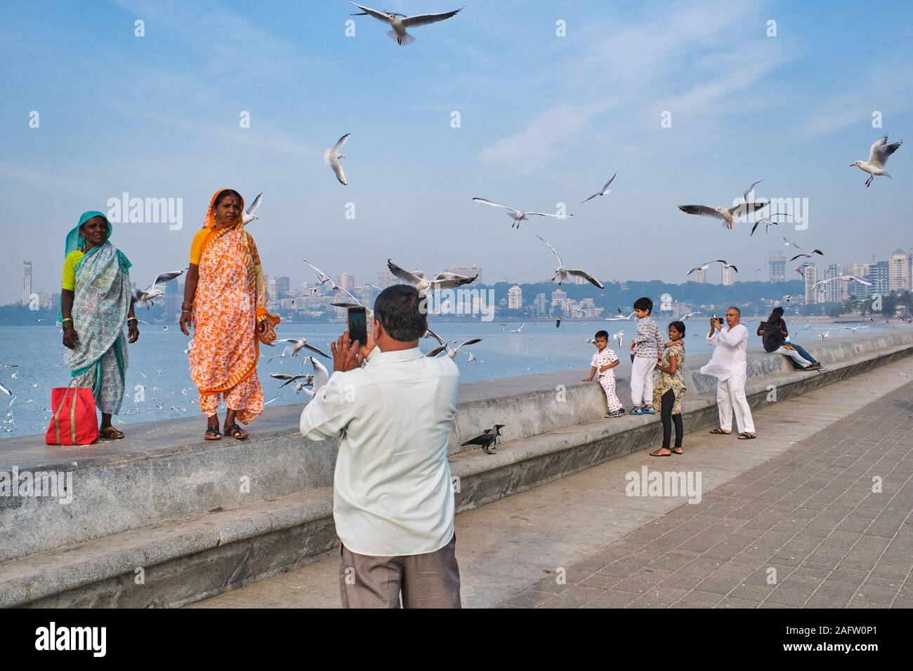 Sul terrapieno iconica Marine Drive, un viale lungomare dal Mare arabico in Mumbai, India, due donne dalla campagna posa per fotografie Foto Stock