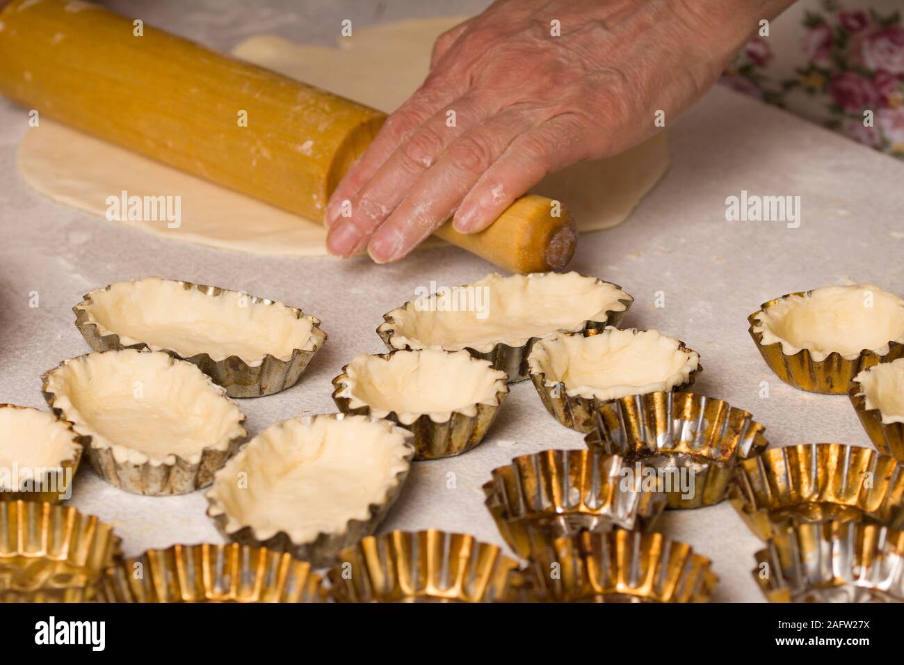 Impasto crudo in lattine tartlet sul vassoio da forno. Non cotti base di pastafrolla per torta in tartlet teglie su un vassoio da forno. redients per rendere l'impasto e tartlet padelle Foto Stock
