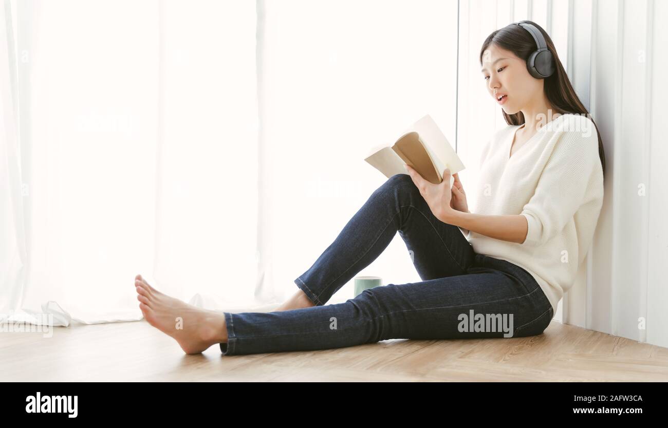 Ritratto di donna asiatica la lettura del libro e rilassante con il caffè a casa. Foto Stock