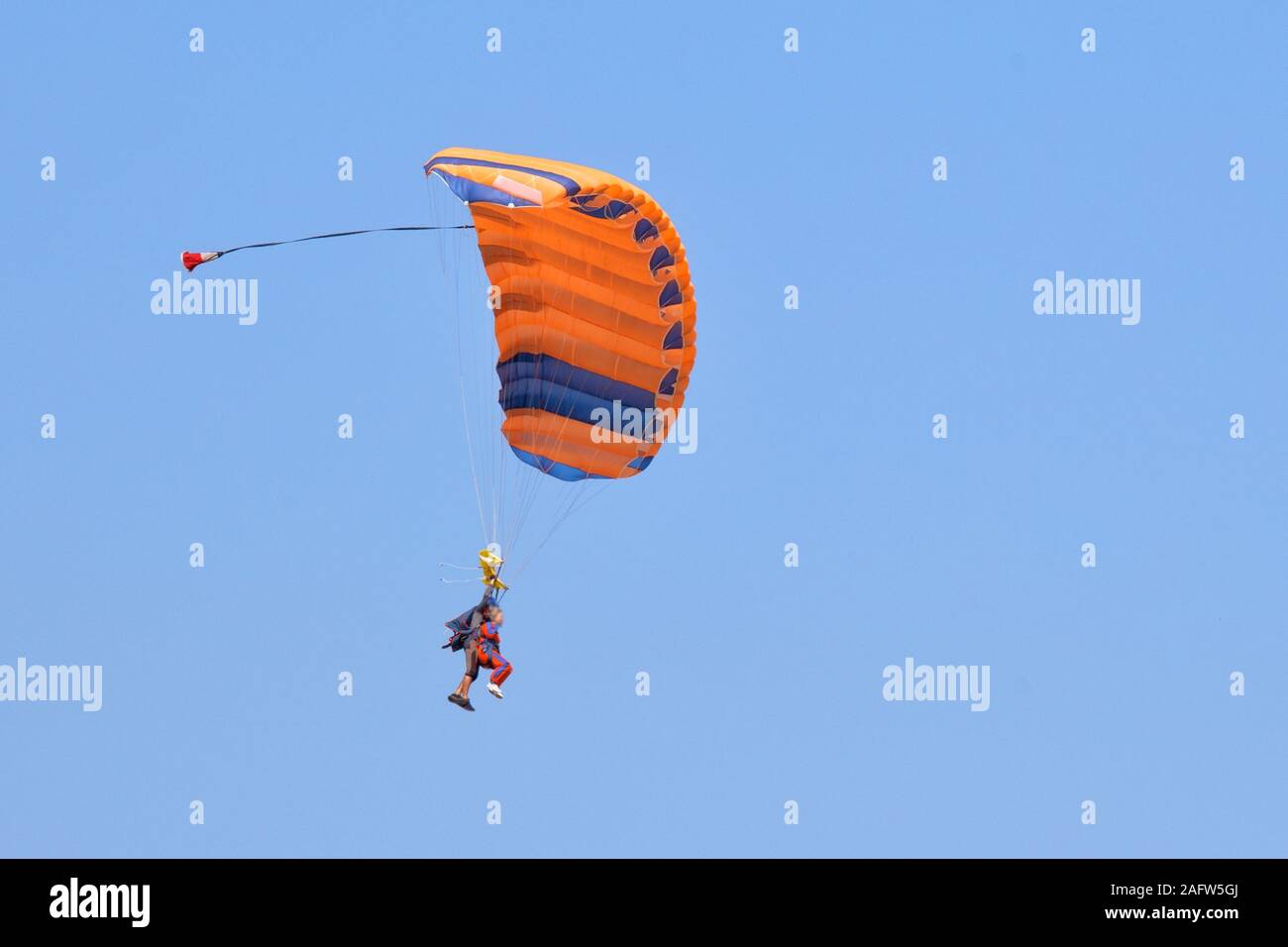 Il tandem parachute jump. Insegnante e studente volare sotto la cupola di un paracadute arancione nel cielo Foto Stock