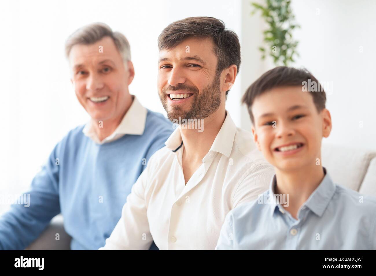 Felice Middle-Aged uomo Con figlio e padre anziano seduta Indoor Foto Stock