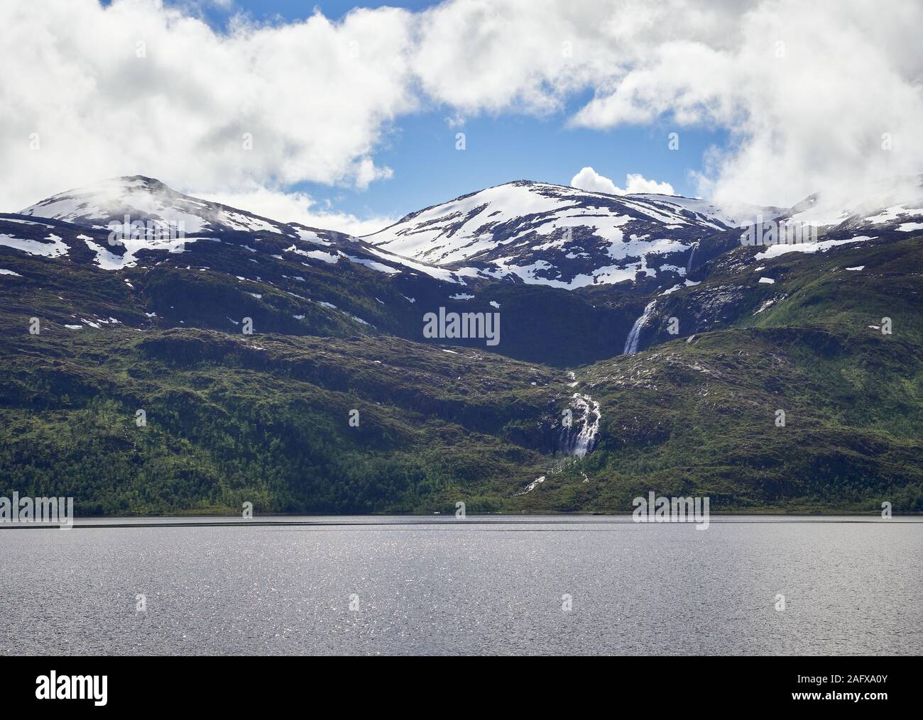 Nord del paesaggio con montagne e foreste in primo piano e il picco di montagna e cascata sullo sfondo. Senja Isola, Troms County, Norvegia. Foto Stock