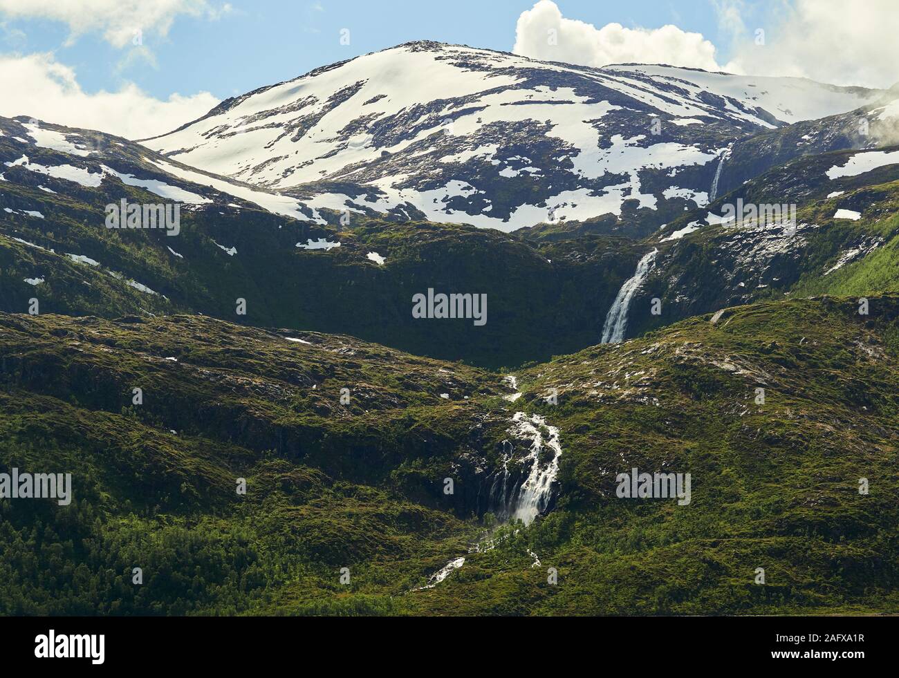 Nord del paesaggio con montagne e foreste in primo piano e il picco di montagna e cascata sullo sfondo. Senja Isola, Troms County, Norvegia. Foto Stock