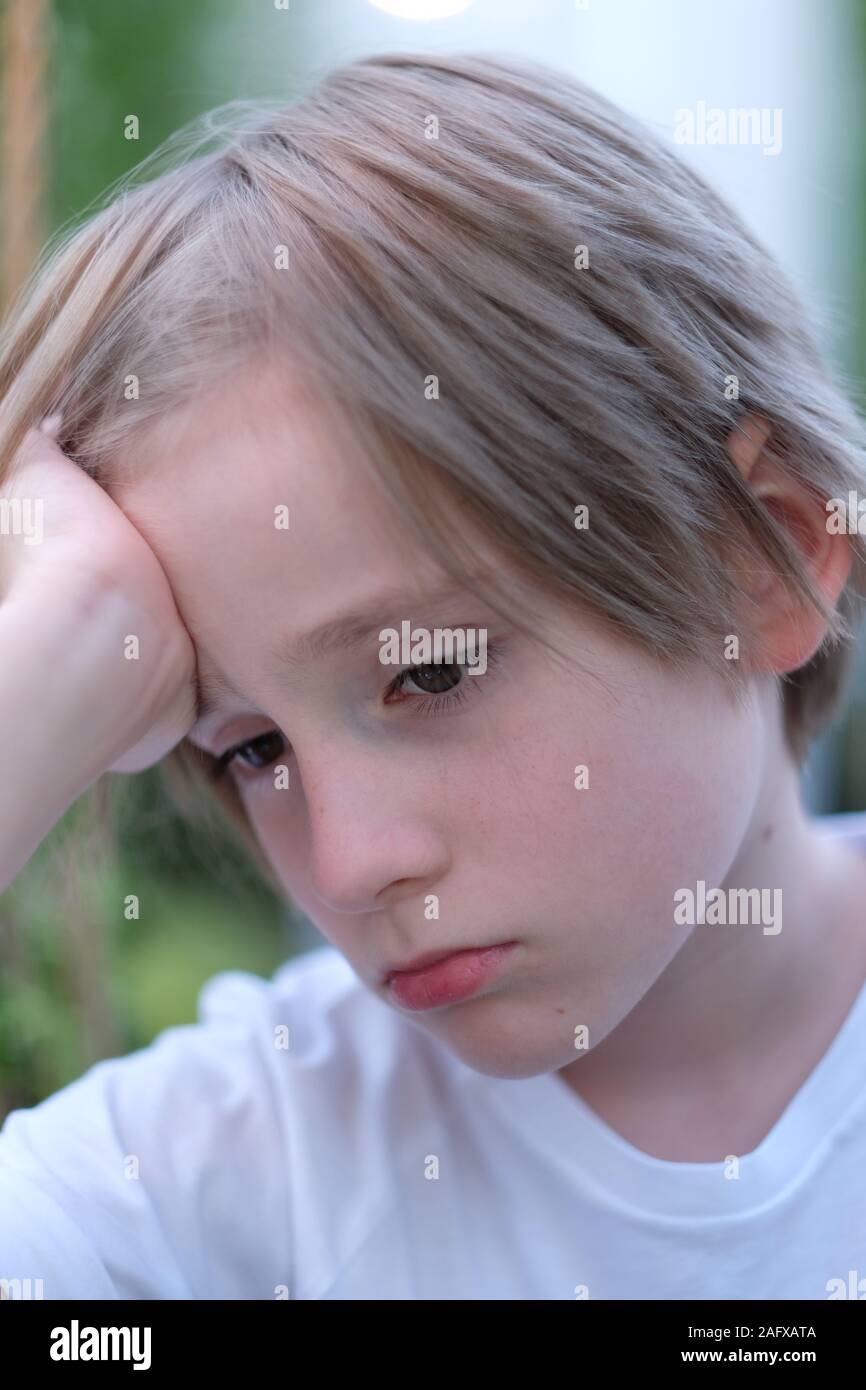 Ritratto di una scuola-ragazzo di età con la sua mano sulla sua testa e con la tristezza nei suoi occhi Foto Stock