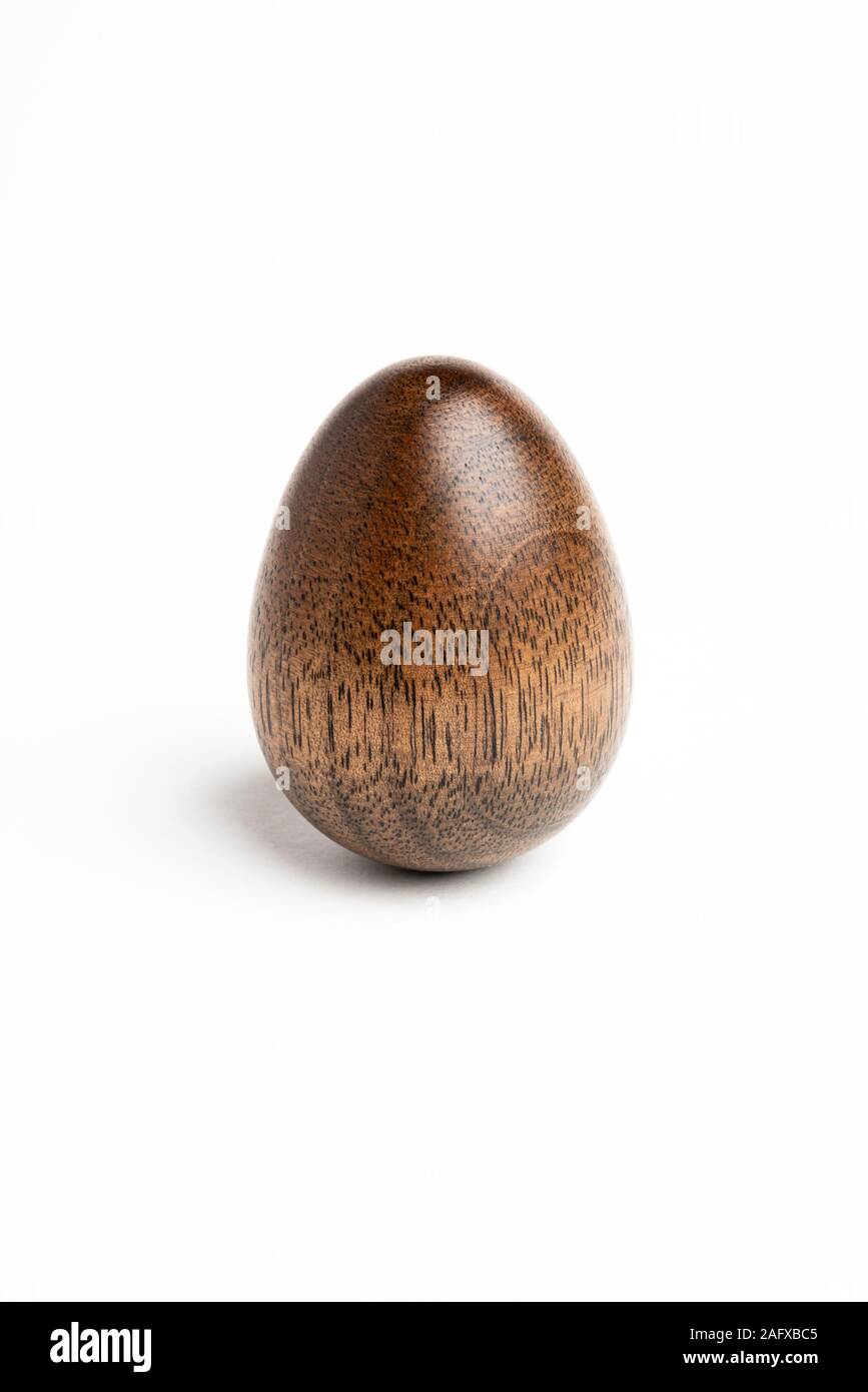 Un semplice pezzo scultoreo raffigurante la forma di un uovo permanente realizzato in legno duro con un distintivo texture lucido. Foto Stock
