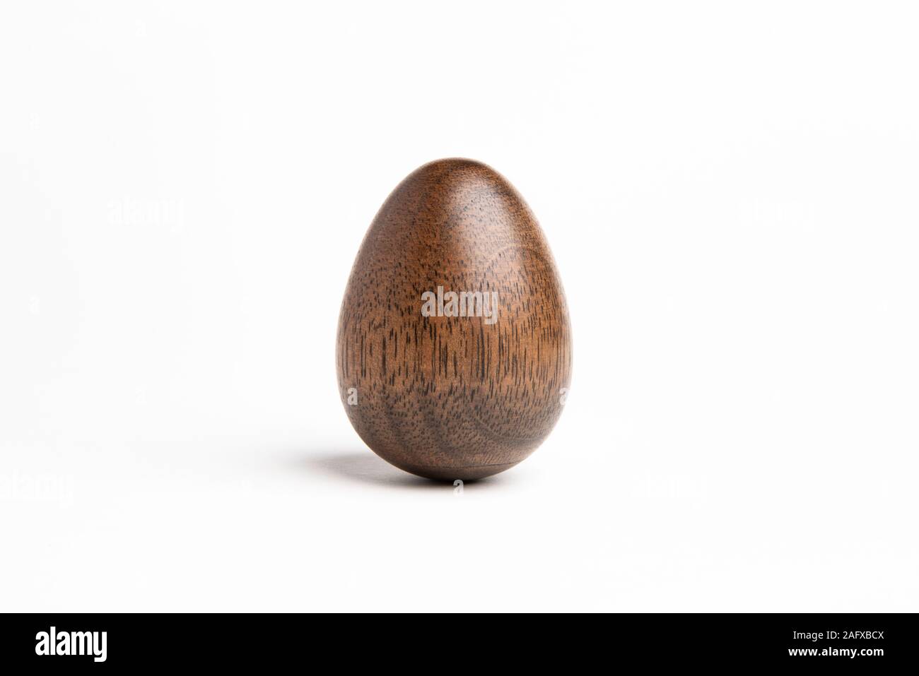Un semplice pezzo scultoreo raffigurante la forma di un uovo permanente realizzato in legno duro con un distintivo texture lucido. Foto Stock