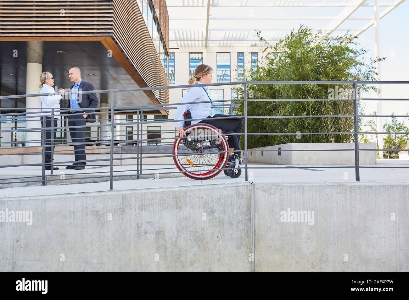 Una donna su una sedia a rotelle viaggiano su una rampa per accessibilità e inclusione Foto Stock