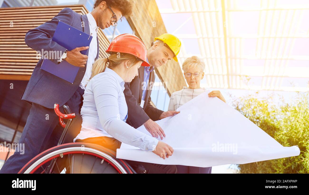 Edificio privo di barriere con una donna su una sedia a rotelle quando la pianificazione della costruzione come un team Foto Stock
