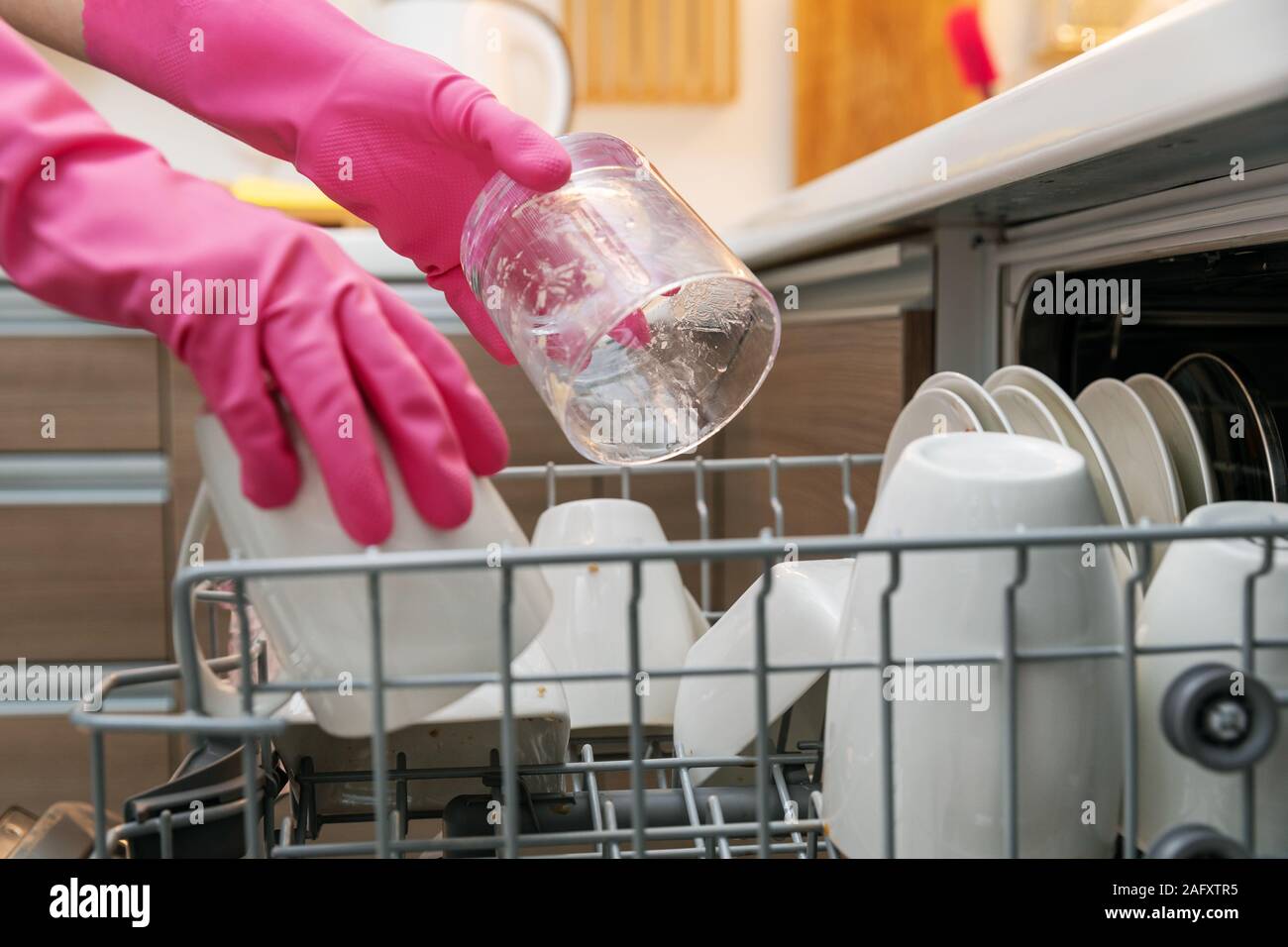 Casalinga mettendo stoviglie sporche in cestello di lavastoviglie in cucina domestica Foto Stock