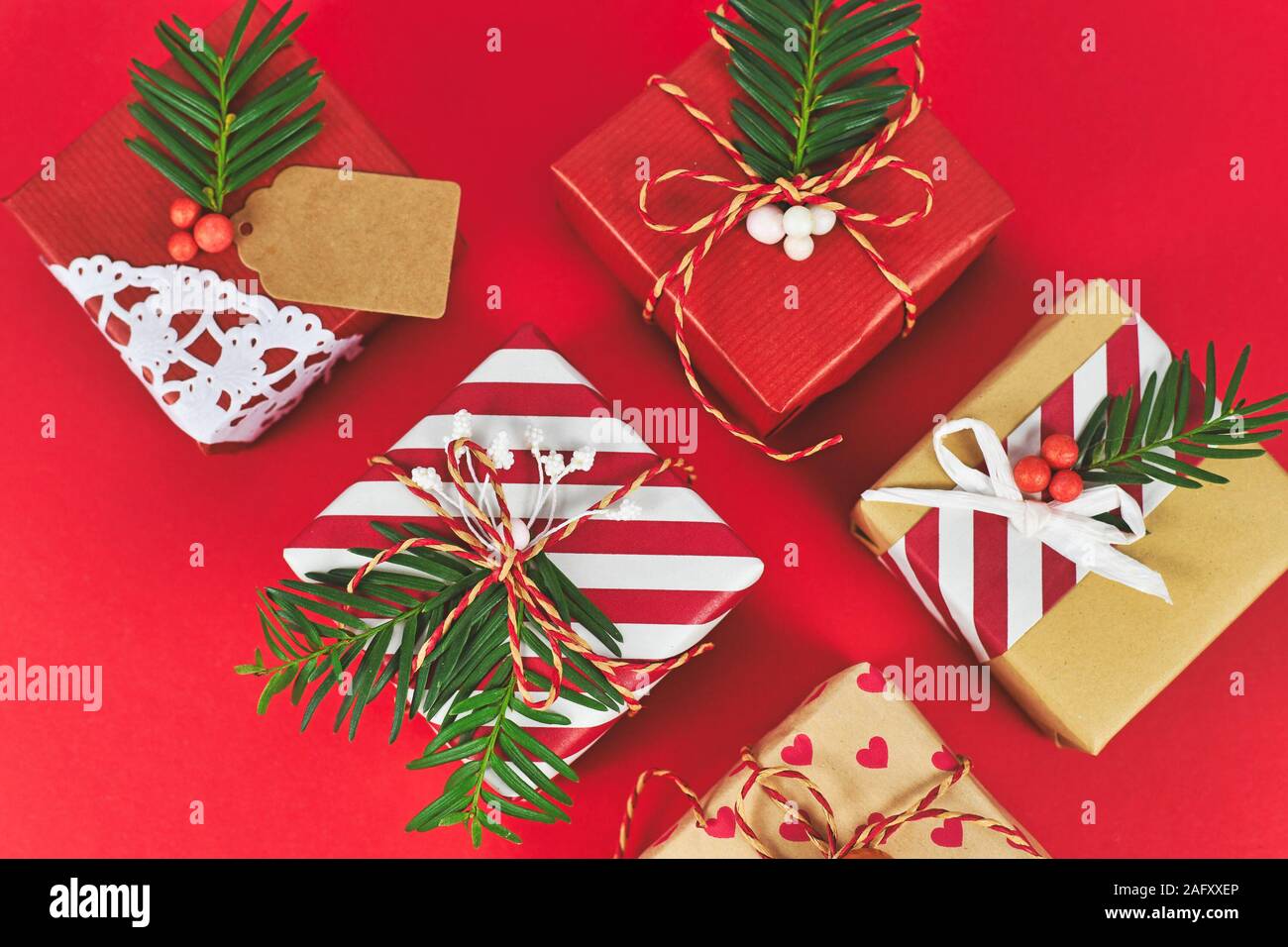 Vista superiore del bel rosso, bianco e marrone naturale decorato di Natale confezioni regalo con nastri e rami d abete su sfondo rosso Foto Stock