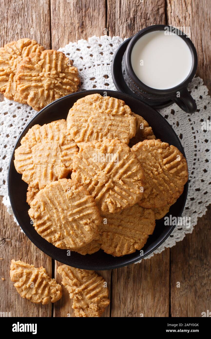 Appena sfornato il burro di arachidi cookie con un bicchiere di latte vicino sul tavolo. Verticale in alto vista da sopra Foto Stock