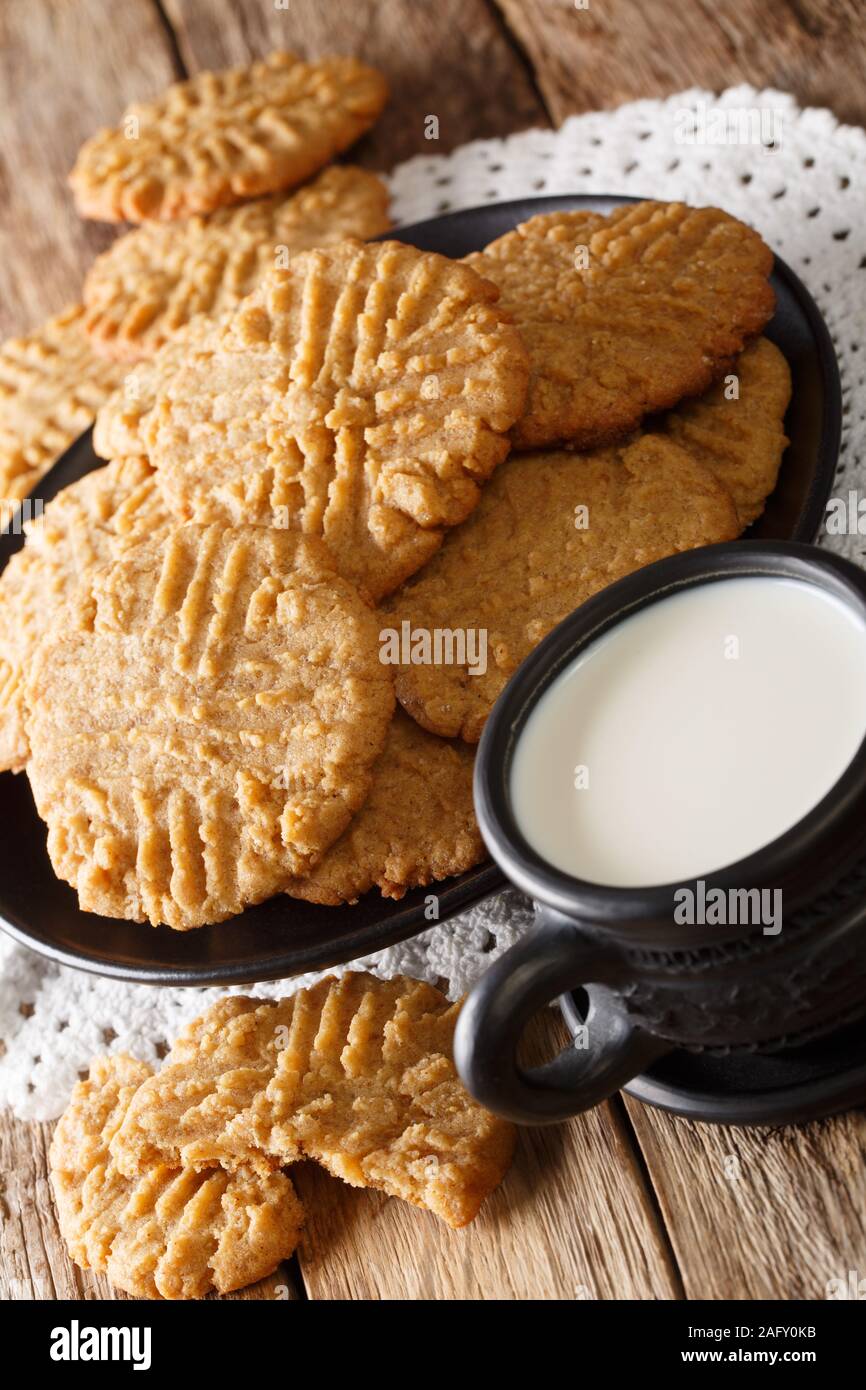 Appena sfornato il burro di arachidi cookie con un bicchiere di latte vicino sul piano verticale. Foto Stock