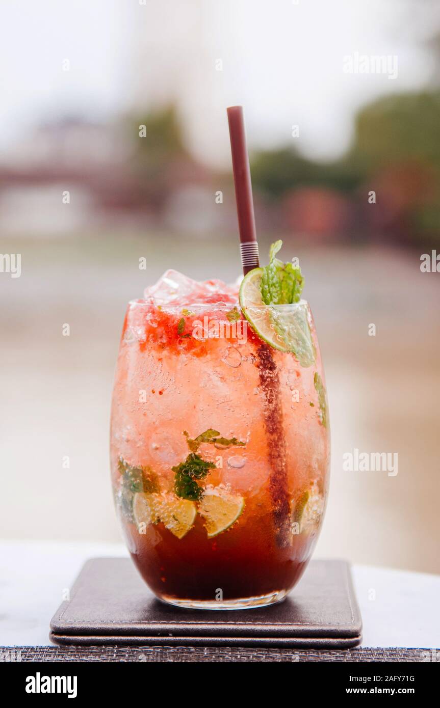 Freddo fresco dolce e aspro red cocktail mojito nella bella di vetro con fettine di lime e foglie di menta Foto Stock