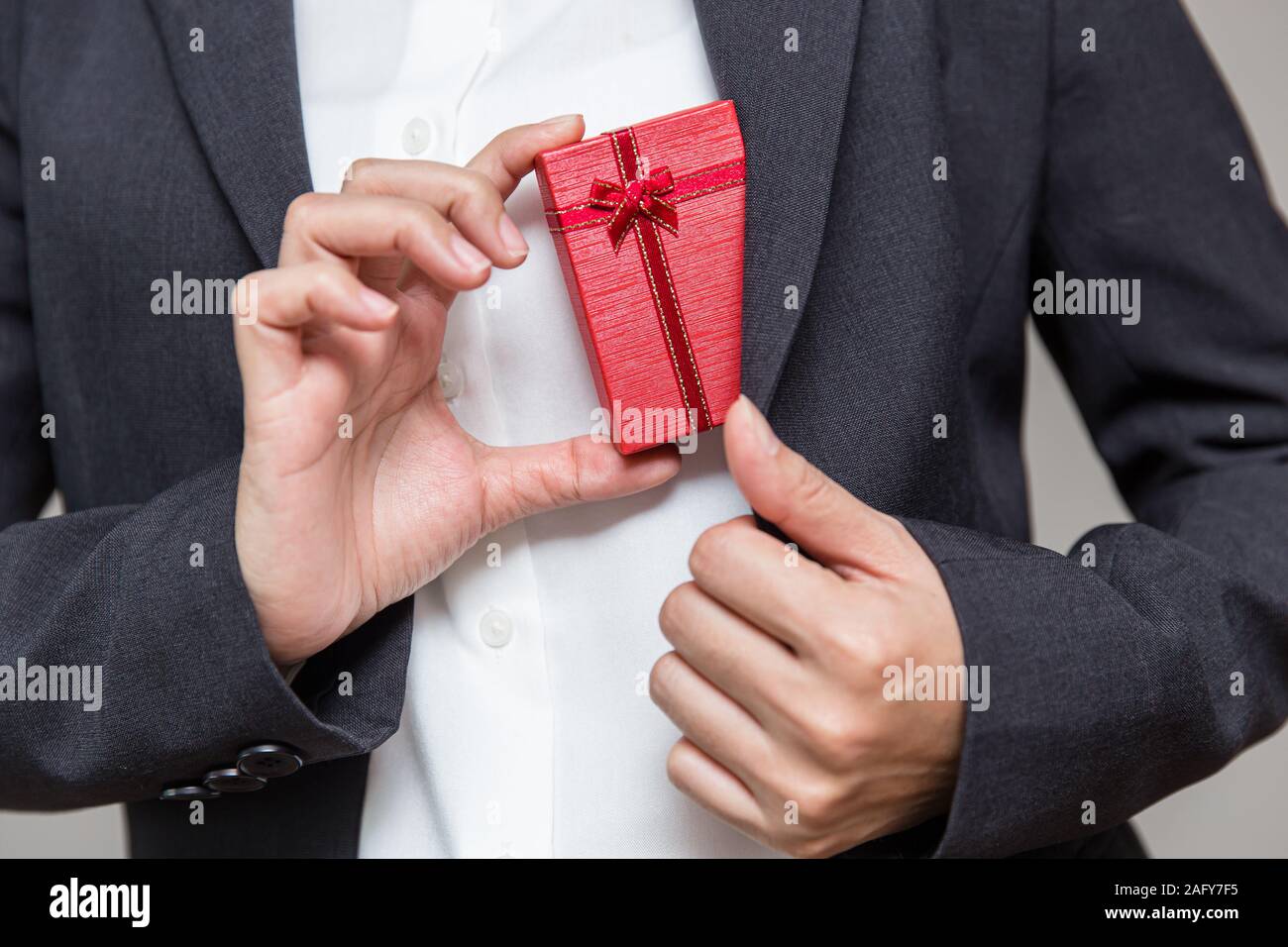 Imprenditore tira una confezione regalo al di fuori della sua tuta per dare la loro azienda lavoratore per fine anno bonus di grandi dimensioni. Foto Stock