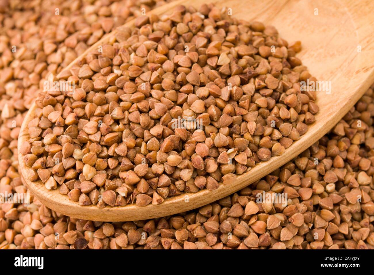 Il grano saraceno in un cucchiaio di legno. Sul tavolo di legno Foto Stock