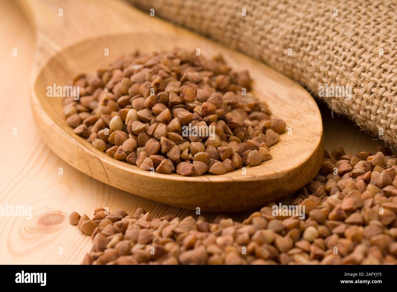 Il grano saraceno in un cucchiaio di legno. Sul tavolo di legno Foto Stock