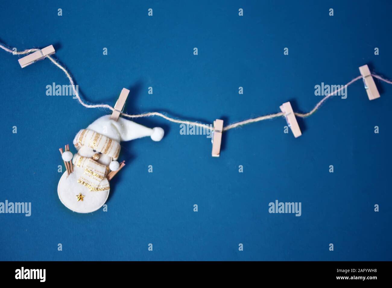 Natale in miniatura giocattolo divertenti pupazzo di neve appesi i vestiti pin su uno sfondo blu. Blu classico colore trend 2020 anno. Foto Stock
