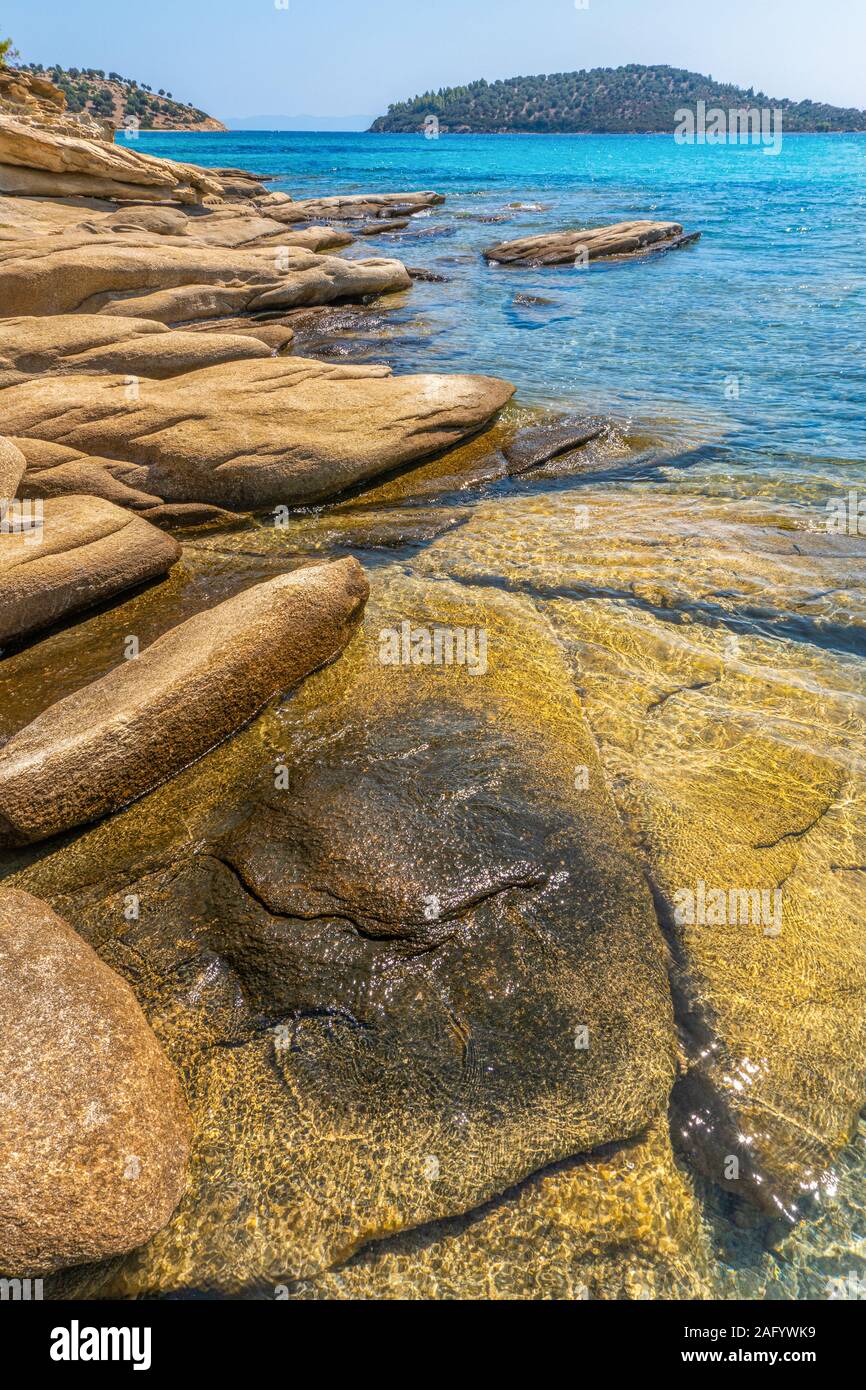 Grandi pietre gialle sotto acqua in Grecia in verticale Foto Stock