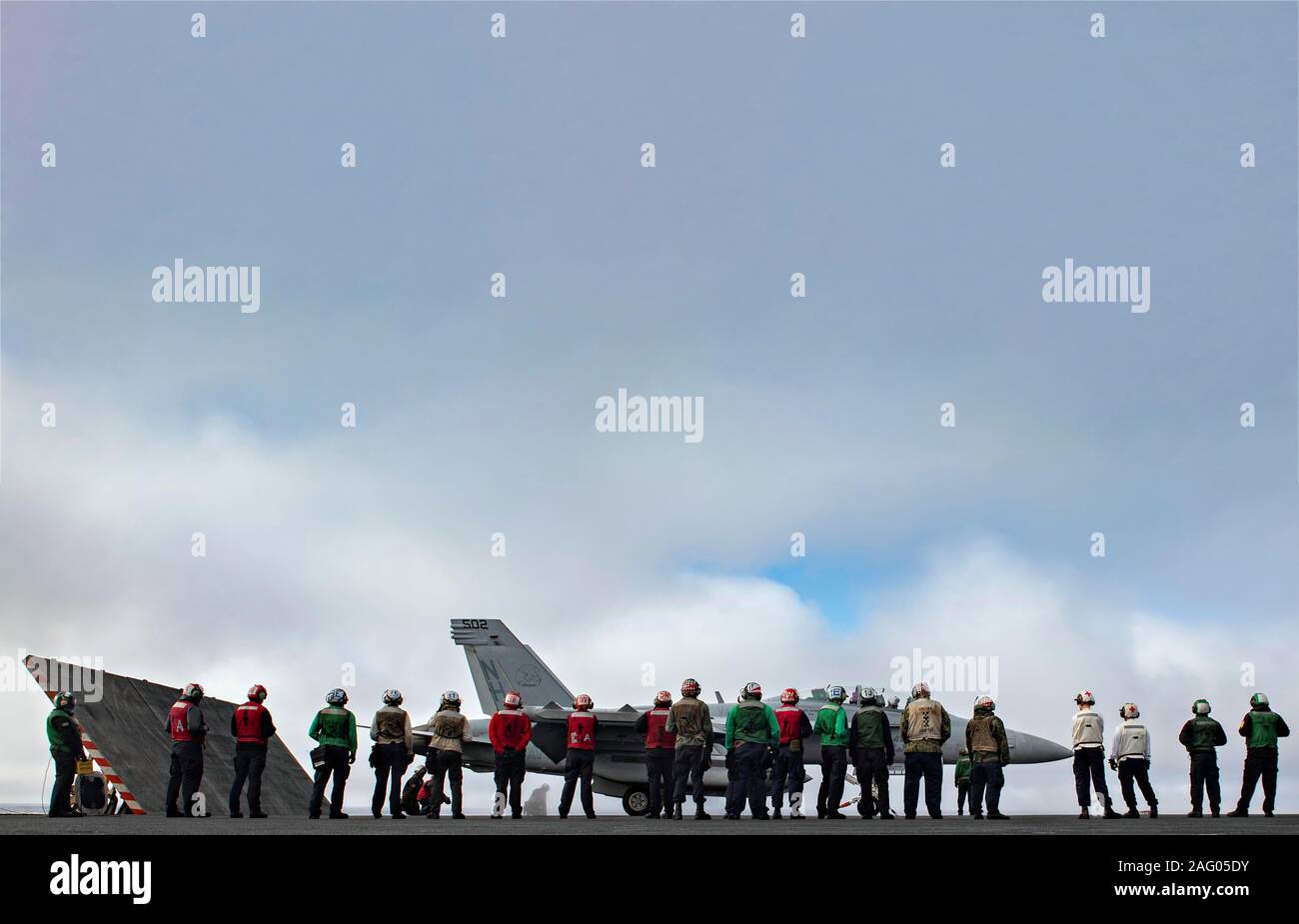Stati Uniti I marinai della marina guarda una E/A-18 Growler Fighter Aircraft, assegnati ai Lupi grigi di Attacco Elettronico Squadron 142, prima che si lancia dal ponte di volo dell'Nimitz-class portaerei USS Theodore Roosevelt durante le normali operazioni di formazione 16 dicembre 2019 nell'Oceano Pacifico. Foto Stock