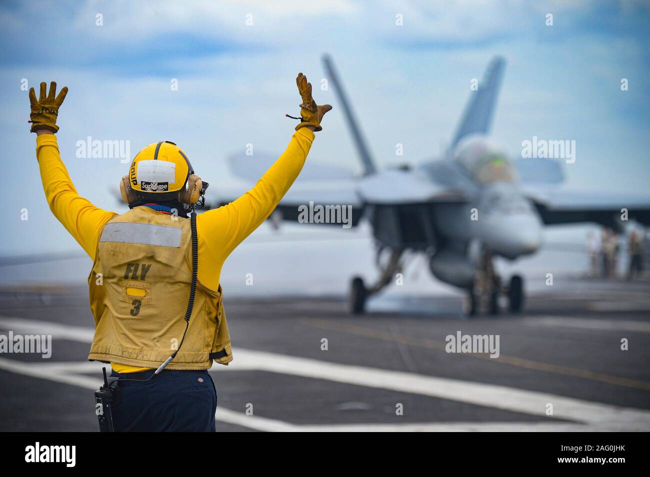Stati Uniti Navy sailor Dylan Allsopp segnali l'F/A-18 Super Hornet fighter aerei di atterraggio sul ponte di volo dell'Nimitz-class portaerei USS Harry Truman a sostegno di funzionamento inerenti risolvere 11 dicembre 2019 nel mar Mediterraneo. Foto Stock