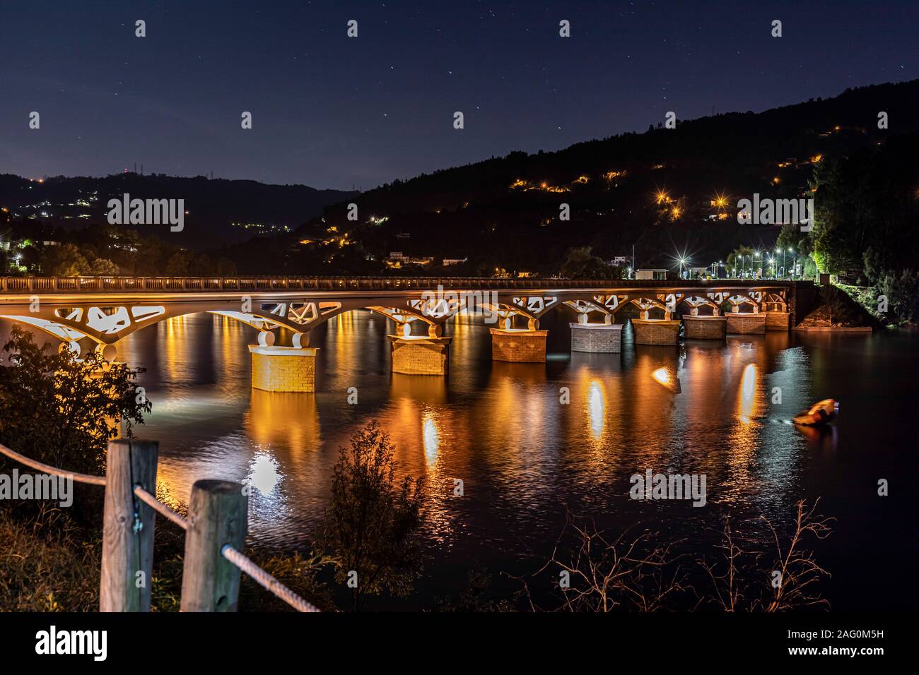 Di notte, il ponte illuminato attraverso il fiume Cavado. Peneda-Gerês National Park, il Parque Nacional da Peneda-Gerês, il lago a Ponte, Portogallo Foto Stock