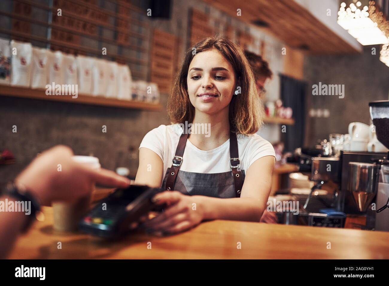 Il pagamento utilizzando il sistema digitale. Femmina e giovane lavoratore cafe all'interno. Concezione di business e del servizio Foto Stock