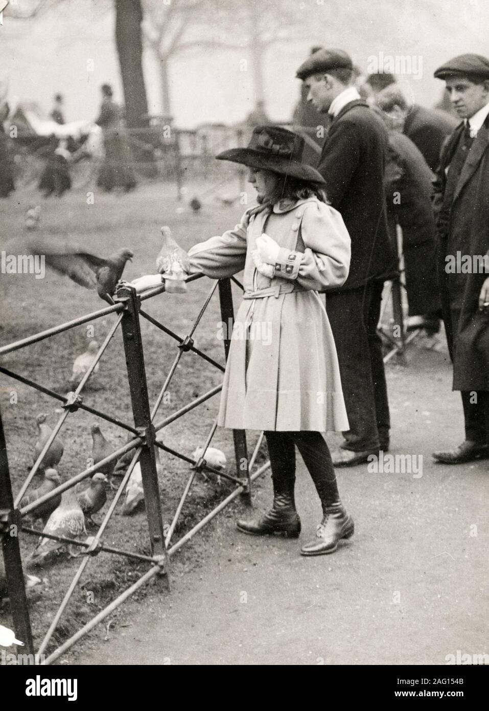 Nei primi anni del XX secolo vintage premere fotografia - una ragazza di alimentare gli uccelli in Hyde Park a Londra per un giorno di primavera, c.1920s Foto Stock