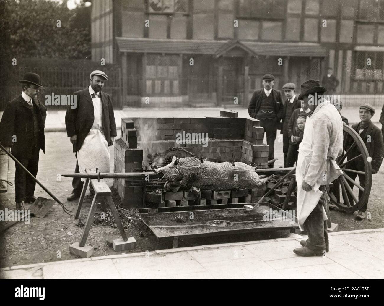 Nei primi anni del XX secolo vintage premere fotografia - uomini tostatura di un maiale allo spiedo in strada, da qualche parte nel Regno Unito c.1920s Foto Stock