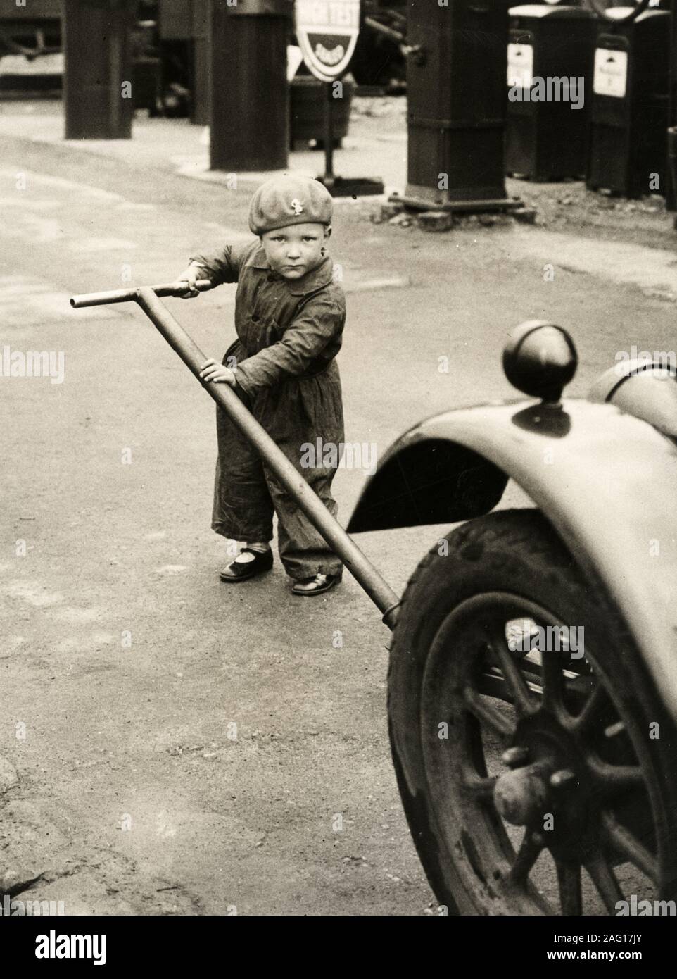 Nei primi anni del XX secolo vintage premere fotografia - piccolo bambino in tuta di sollevare una macchina Foto Stock