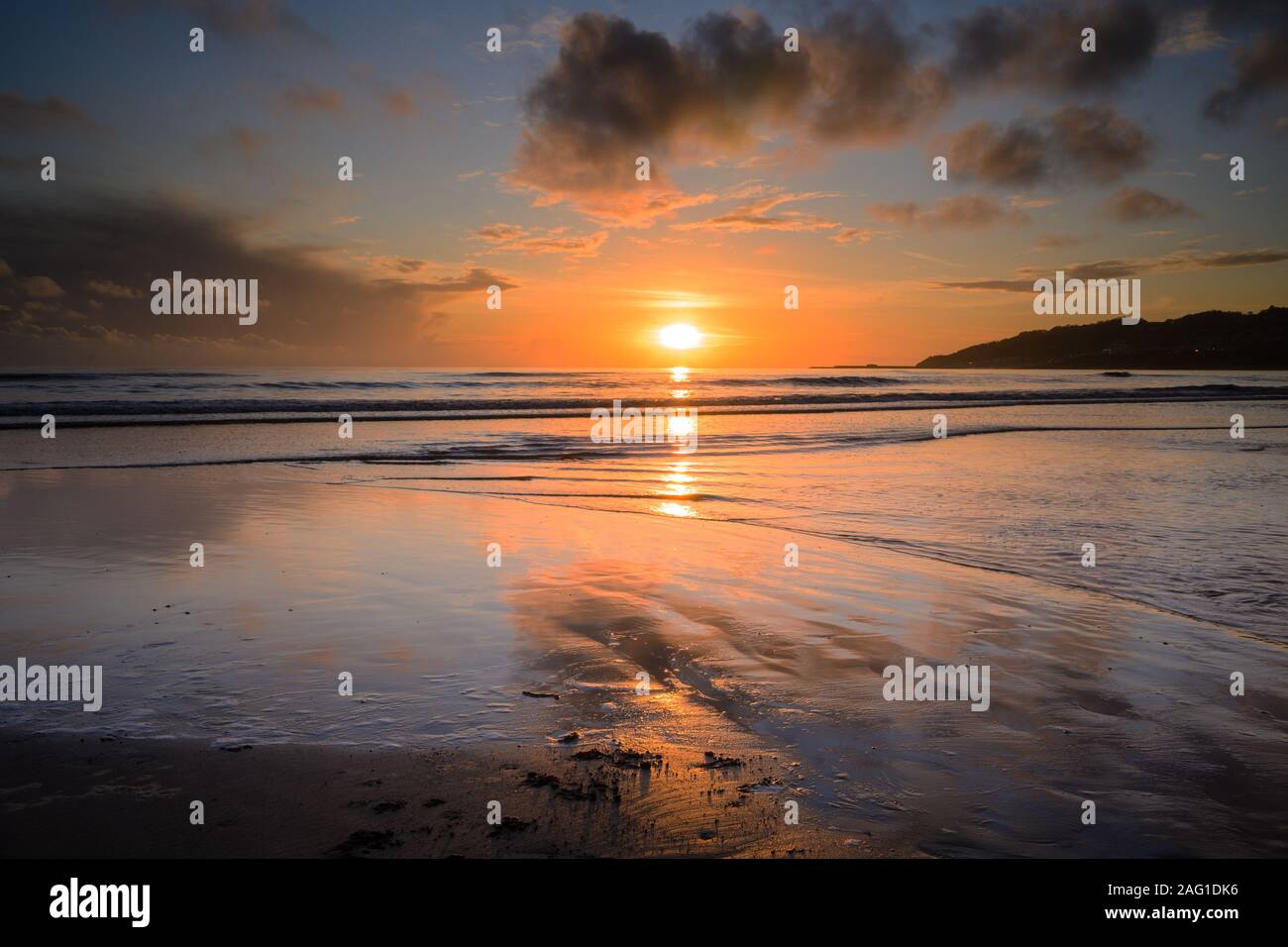 Charmouth, Dorset, Regno Unito. 17 dicembre 2019. Regno Unito: Meteo bellissimi colori nel cielo al tramonto si riflettono nella sabbia bagnata a bassa marea come il sole tramonta sull'orizzonte vicino a Charmouth alla fine di una giornata invernale e. Credito: Celia McMahon/Alamy Live News. Foto Stock