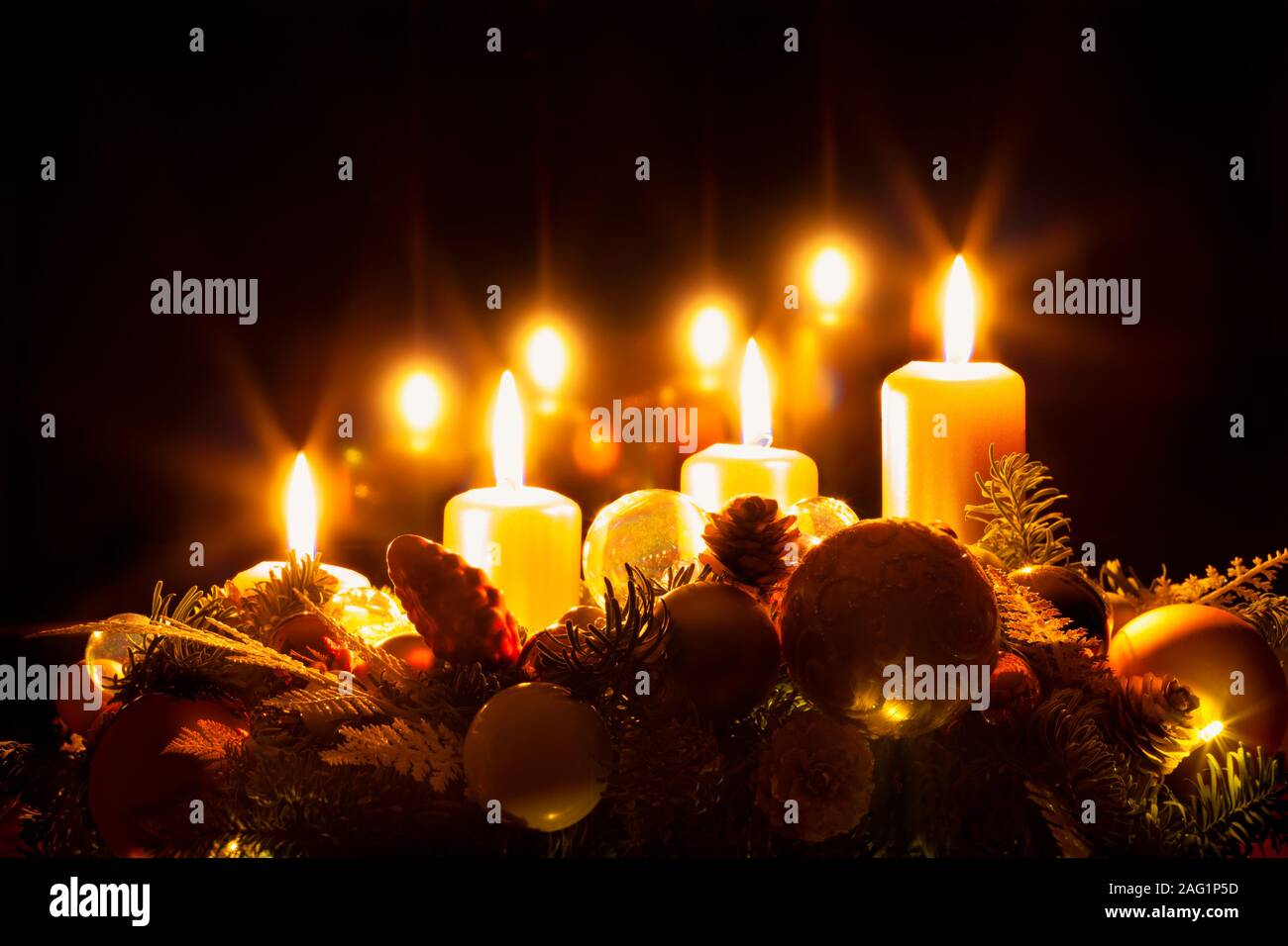 Ghirlanda di Natale con la masterizzazione di quattro candele giallo, tempo di Avvento, la vigilia di Natale, sfondo nero, spazio di copia Foto Stock