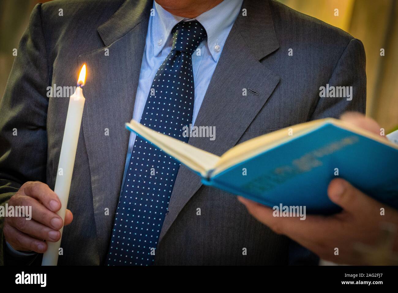 Leggere la Bibbia con la luce del cantante a un battesimo Foto Stock