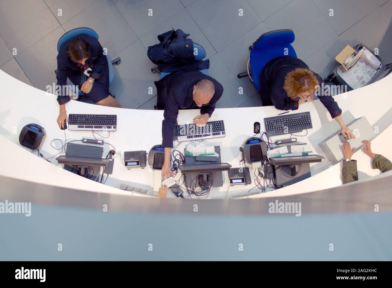 Tre agenti del servizio clienti lavorando a un help desk presso l'aeroporto. Foto Stock