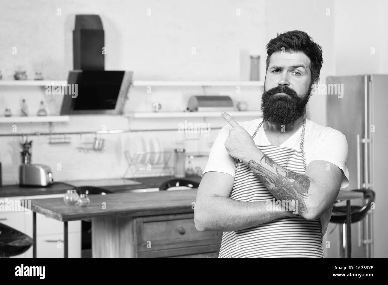 Benvenuti al suo master class in culinario scuola. Felice capitano Cook. Cuoco professionista con lunga barba puntare il dito. Master chef cuoco indossa uniformi in cucina. Prendendo il tempo di padroneggiare abilità. Foto Stock