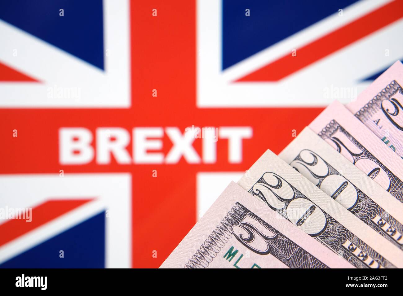 Concetto foto "Prezzo di Brexit'. Sfocato bandiera del Regno Unito con una parola BREXIT e gli angoli delle banconote di dollari sulla parte anteriore. Foto Stock