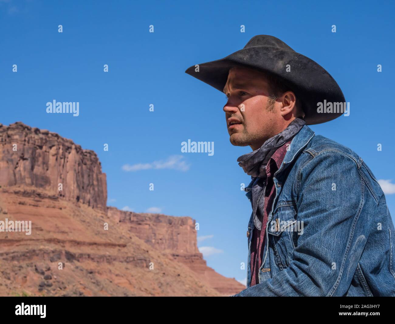 Un gruppo di lavoro di wrangler cowboy in un ranch vicino a Moab, Utah. Dietro sono le scogliere di arenaria del canyon del fiume Colorado. Foto Stock
