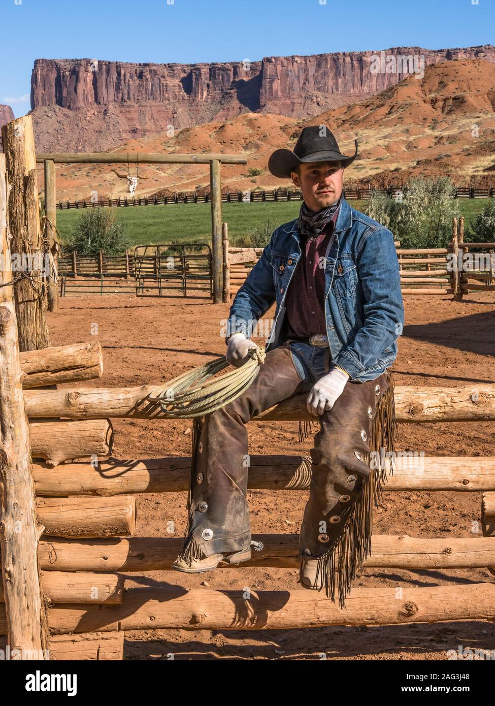 Un lavoro di cowboy wrangler pone con il suo lazo sul Red cliffs ranch vicino a Moab, Utah. Dietro sono le scogliere di arenaria del canyon del Colorad Foto Stock
