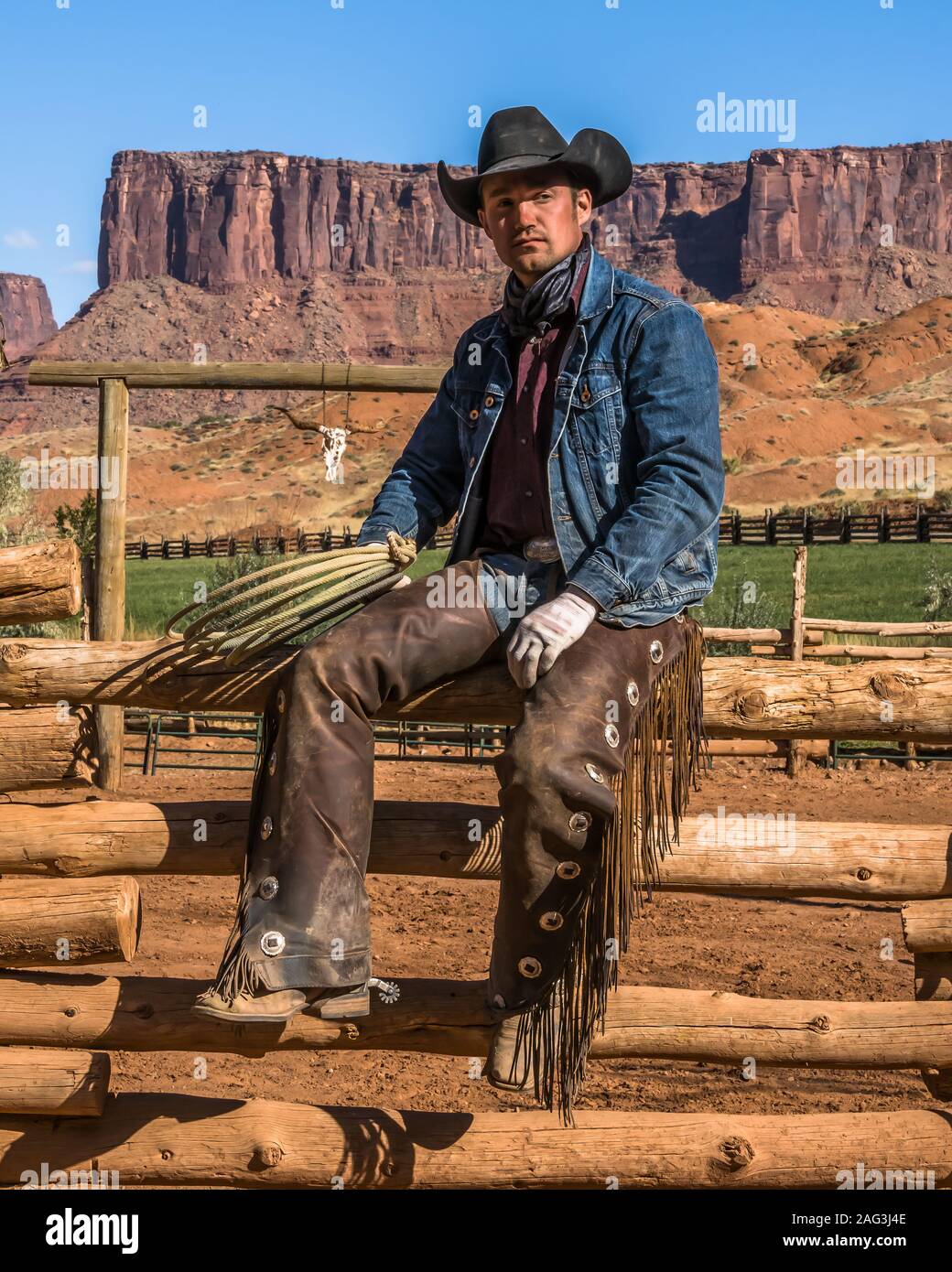 Un lavoro di cowboy wrangler pone con il suo lazo sul Red cliffs ranch vicino a Moab, Utah. Dietro sono le scogliere di arenaria del canyon del Colorad Foto Stock