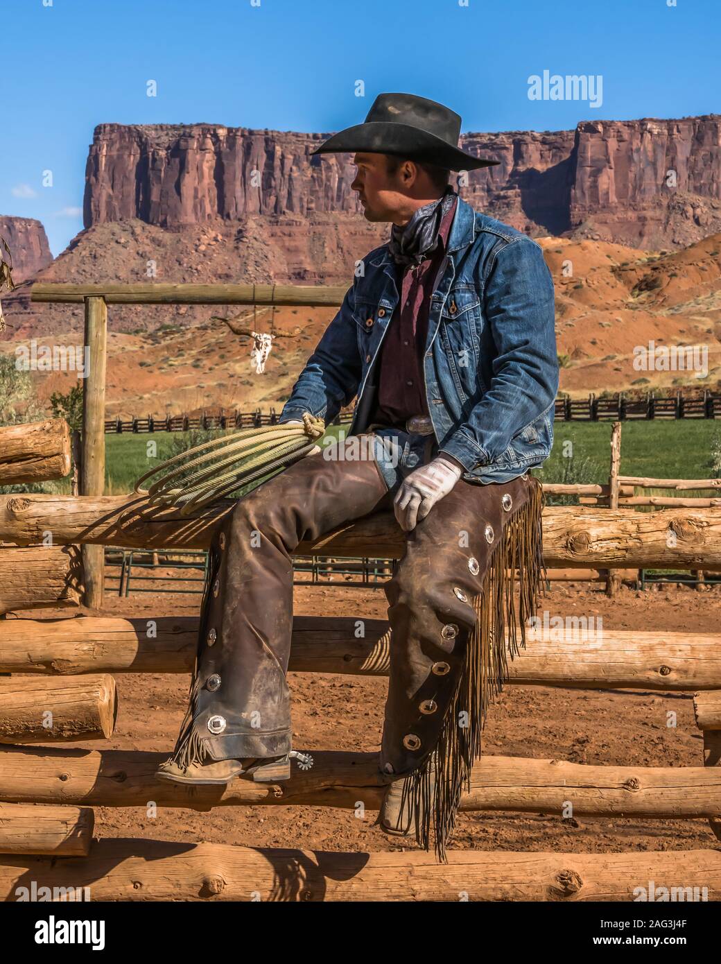 Un lavoro di cowboy wrangler pone con il suo lazo sul Red cliffs ranch vicino a Moab, Utah. Dietro sono le scogliere di arenaria del canyon del Colorad Foto Stock