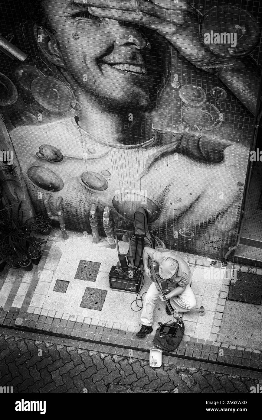 HONG KONG CINA - Feb 06, 2019: musicista giocare davanti a un insoddisfatto street art Foto Stock